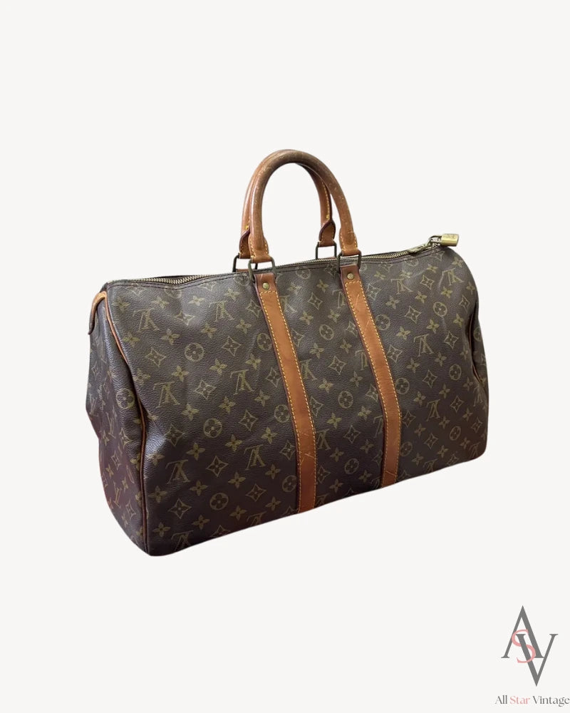 Angled side view of the Louis Vuitton monogram duffle bag with a detailed look at the leather handles and side profile