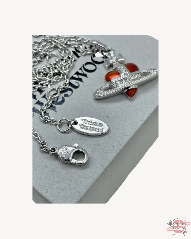 Closeup of Vivienne Westwood Crystal Heart Orb Necklace with silver chain and red heart pendant on branded box. A luxurious statement piece for elegant and bold styles.